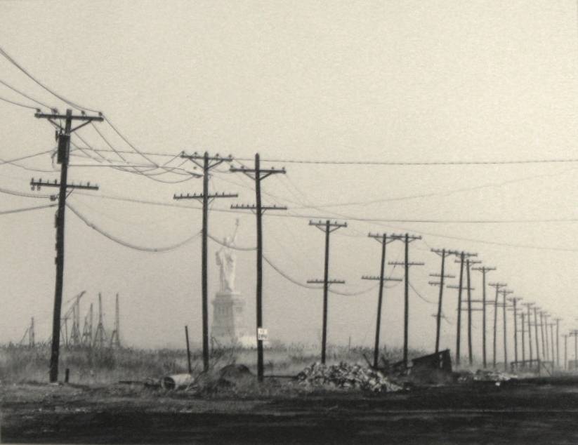 barren road lined with powerlines with the statue of liberty in the background